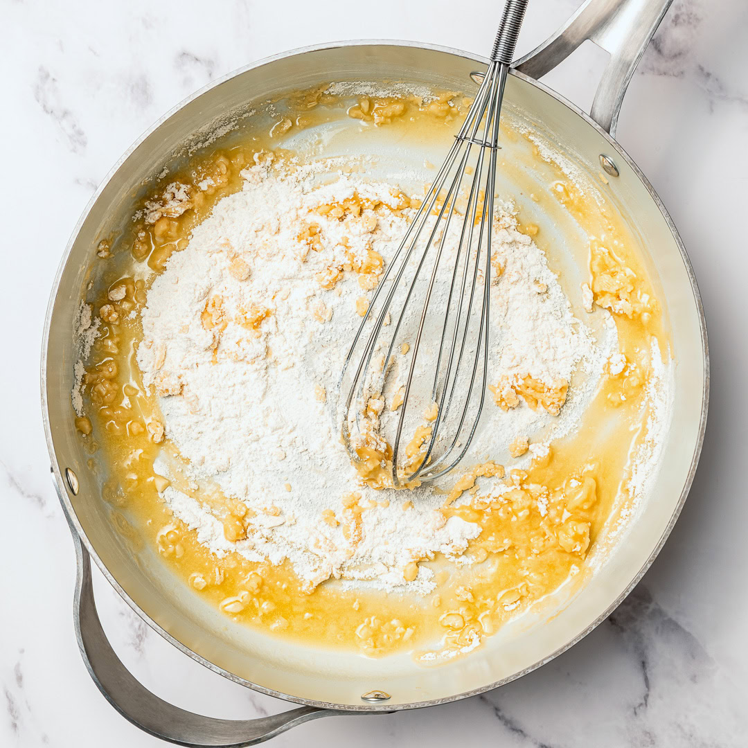 Silky and full of garlicky flavor, this creamy vegan fettuccine Alfredo is the easiest EVER because it's made without nuts or a blender! Whisking vegan roux in skillet.