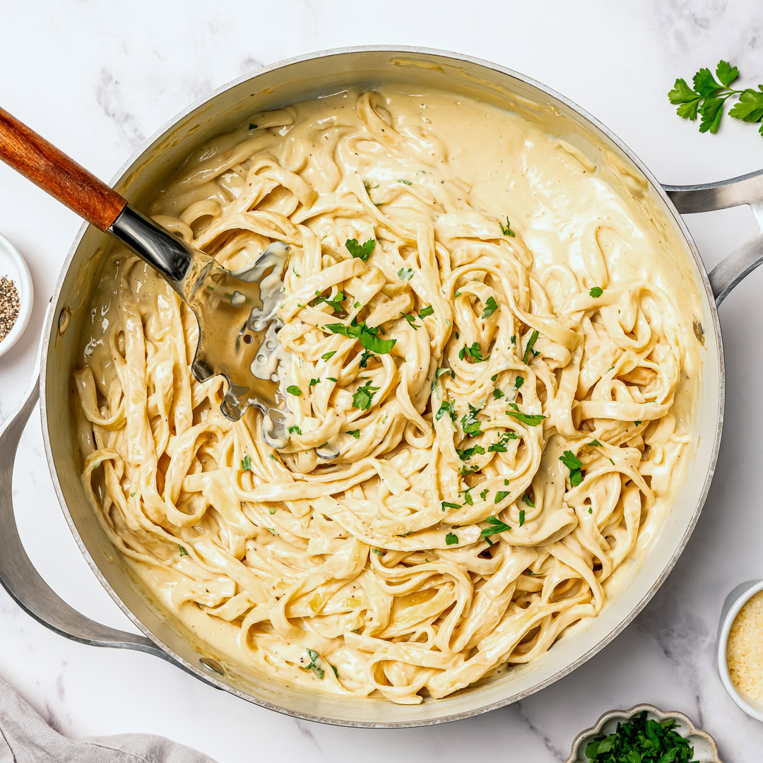 Silky and full of garlicky flavor, this creamy vegan fettuccine Alfredo is the easiest EVER because it's made without nuts or a blender! Vegan fettuccine alfredo in skillet.