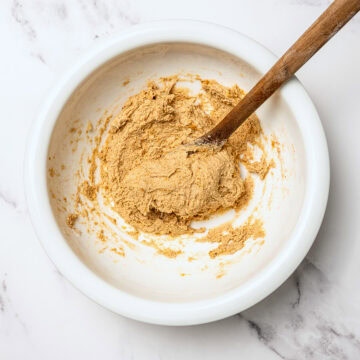Dough for homemade dog treats in bowl with wooden spooon.