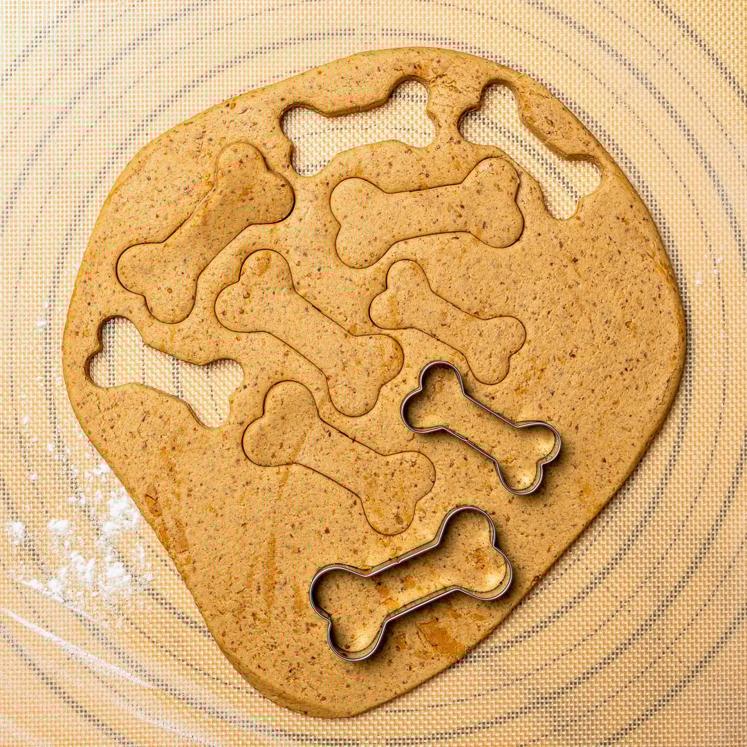 These quick and easy homemade soft dog treats use just 5 simple ingredients and bake up chewy, peanut buttery, and pup-approved! Cookie cutters cutting dough for homemade dog treats.
