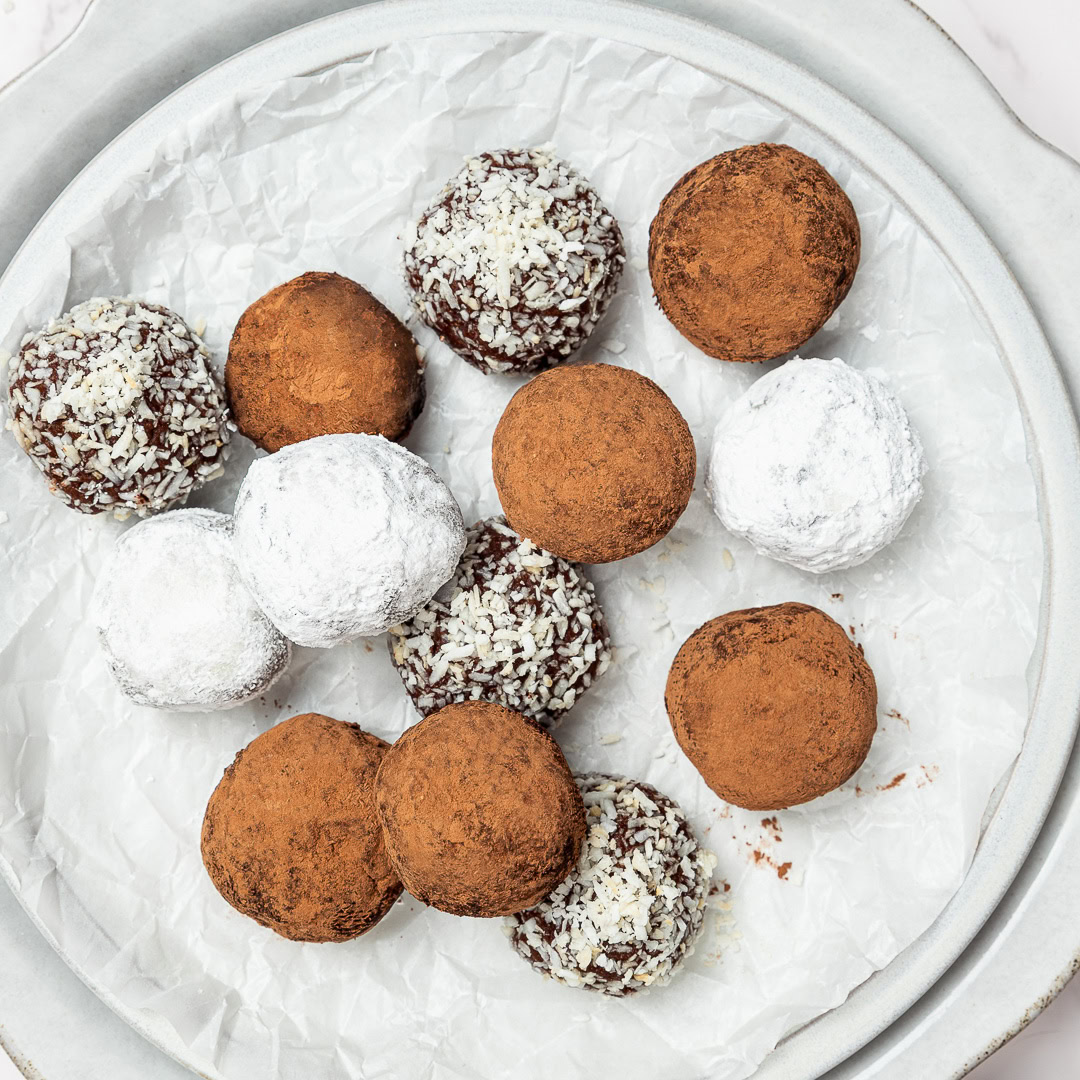 Rich, fudgy Vegan Rum Balls are an easy no-bake holiday treat! Customizable, great for gifting, and delicious with or without alcohol. Vegan rum balls with assorted coatings on plate.