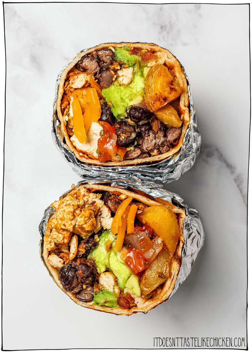 These freezer-friendly vegan breakfast burritos are packed with tofu scramble, crispy potatoes and cheese. Heat and eat for busy mornings! Two foil-wrapped burritos with text overlay that reads vegan breakfast burritos.