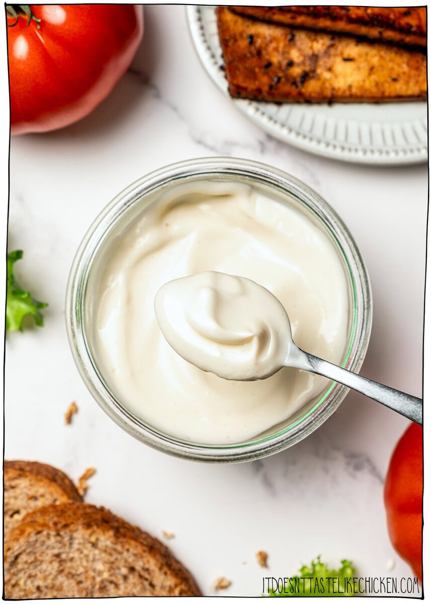 This thick, creamy vegan mayo is made in 5 minutes with soy milk! It’s the BEST fool-proof recipe, egg-free, and better than store-bought. Spoonful of vegan mayo resting on rim of jar.