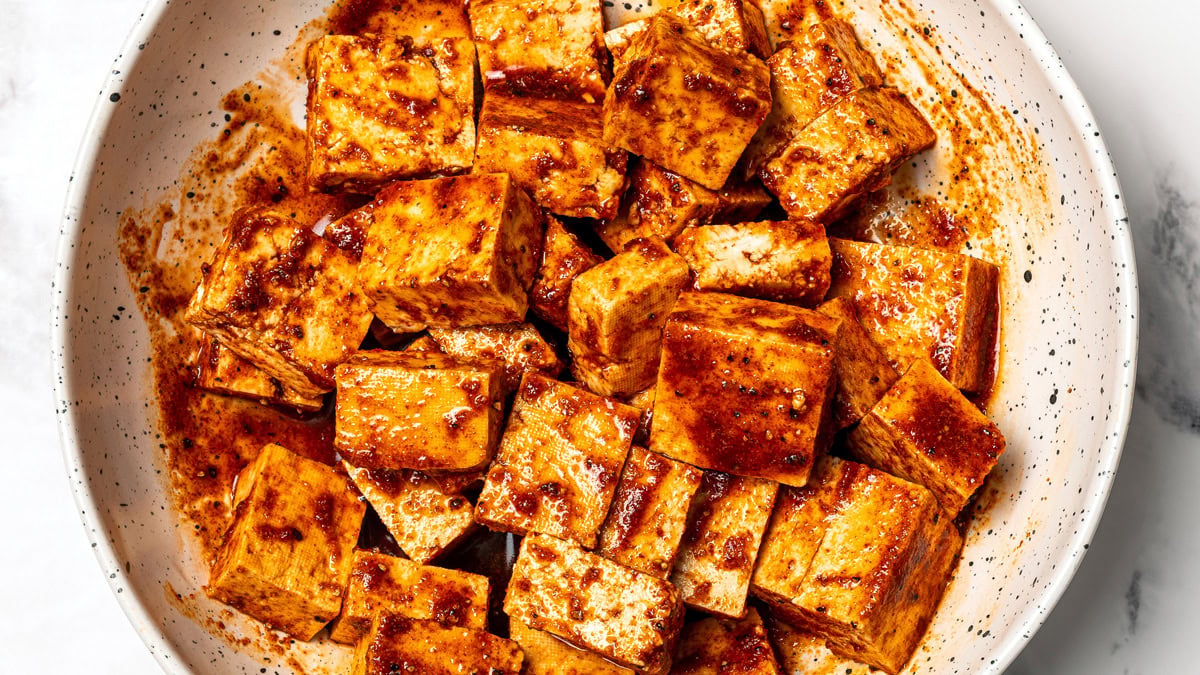 Tofu cubes in bowl with marinade.