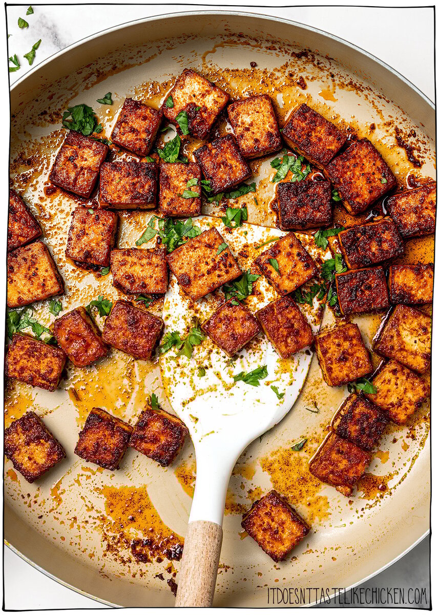 Marinated tofu cubes cooking in skillet with cilantro.