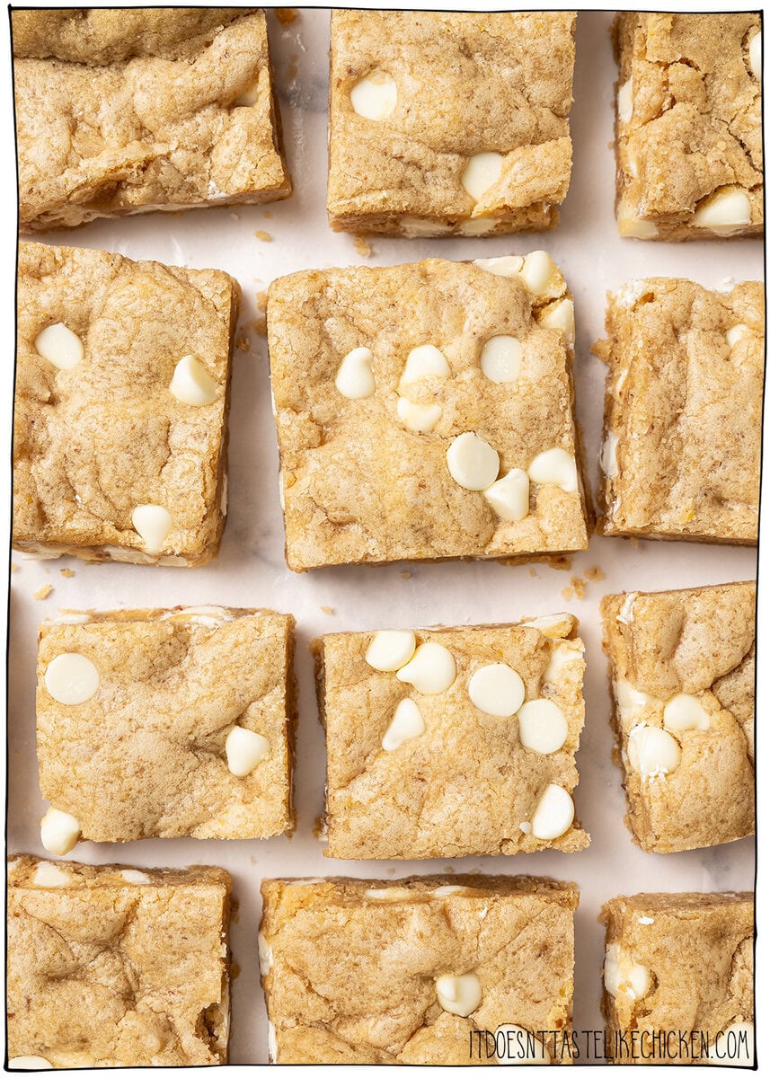 These soft, chewy vegan blondies have rich caramel flavor for bakery-style vibes. An easy one bowl recipe made egg-free and dairy-free! Overhead view of sliced vegan blondies with white chocolate chips.