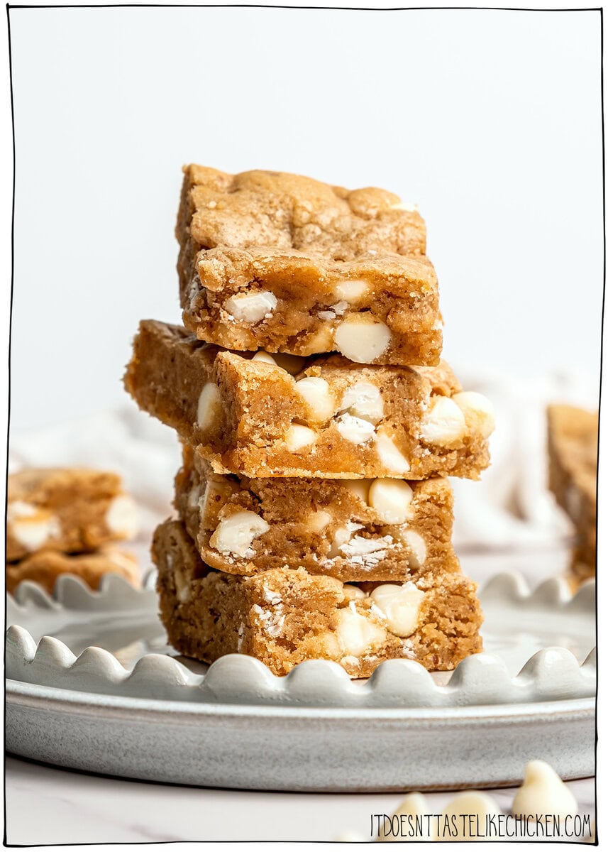 These soft, chewy vegan blondies have rich caramel flavor for bakery-style vibes. An easy one bowl recipe made egg-free and dairy-free! Stack of 4 vegan blondies with white chocolate chips.