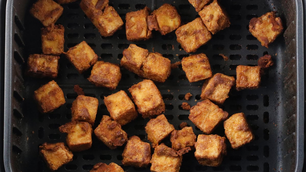 Crispy brown coated tofu in an air fryer basket.