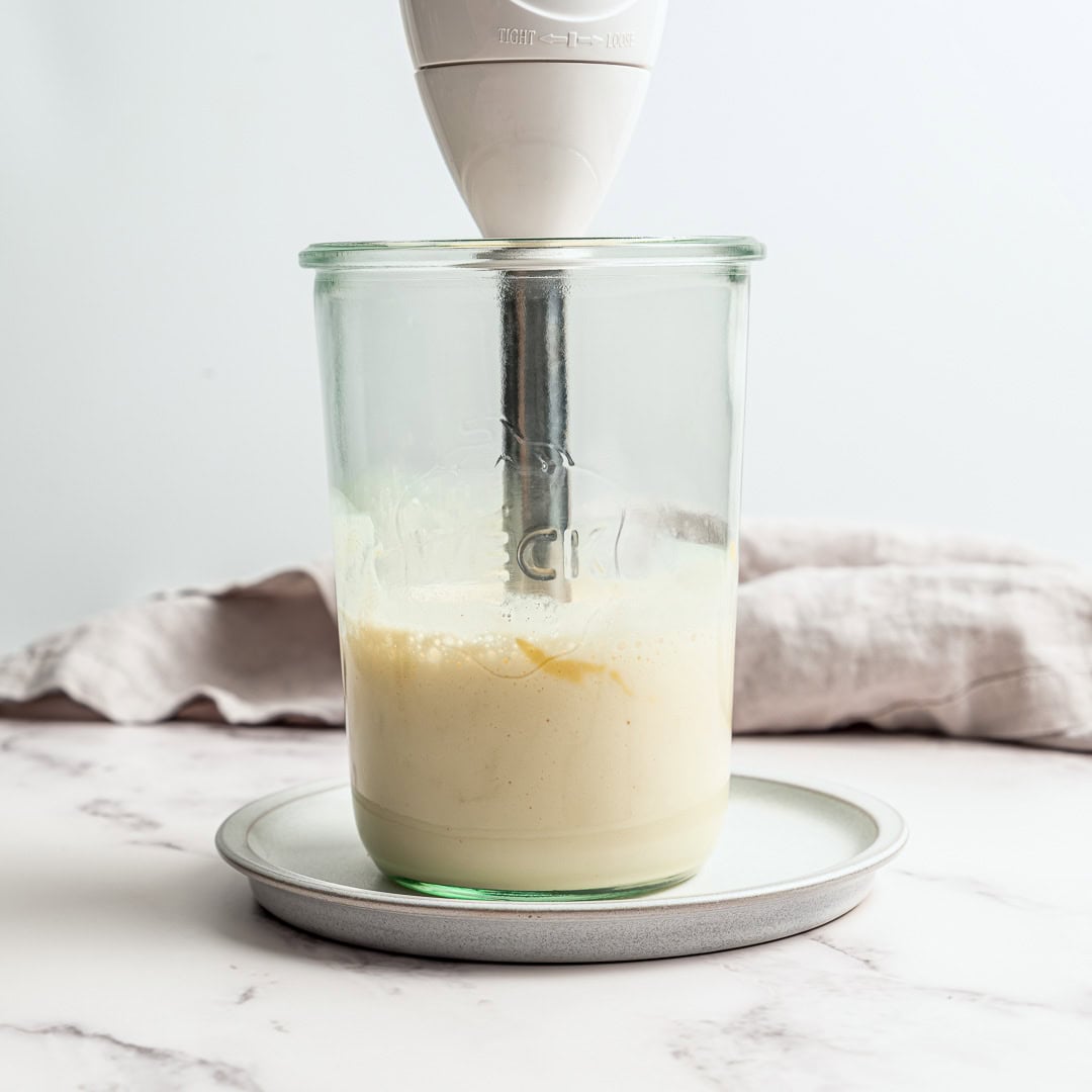 This thick, creamy vegan mayo is made in 5 minutes with soy milk! It's the BEST fool-proof recipe, egg-free, and better than store-bought. Immersion blender in jar with ingredients for vegan mayo.
