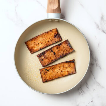 3 slices of vegan bacon in skillet.