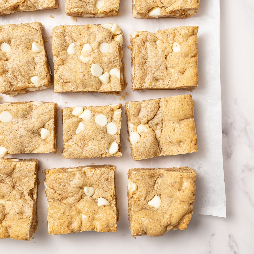 These soft, chewy vegan blondies have rich caramel flavor for bakery-style vibes. An easy one bowl recipe made egg-free and dairy-free! Sliced vegan blondies with white chocolate chips.