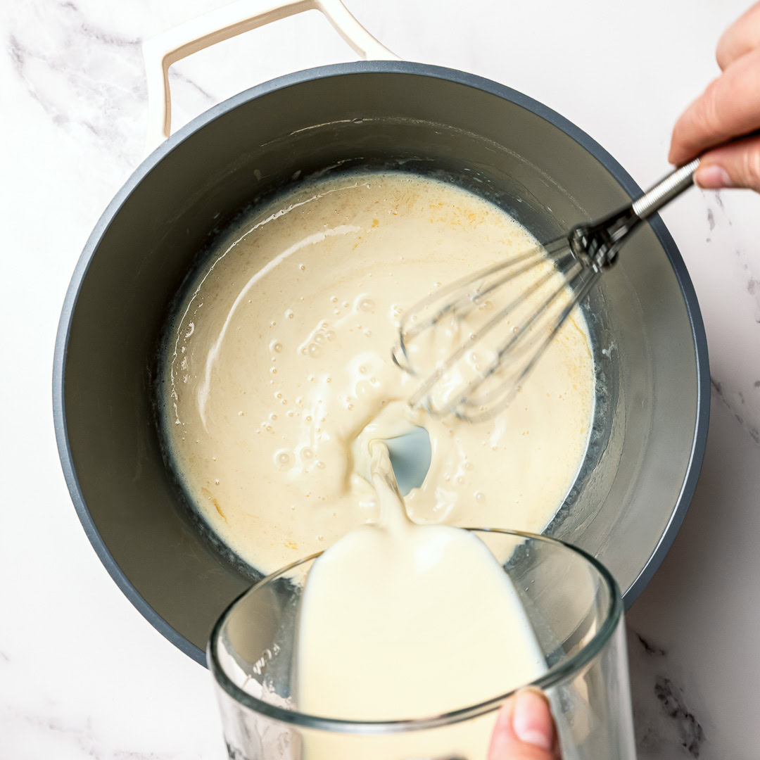 Whisking soy milk into pot of roux.