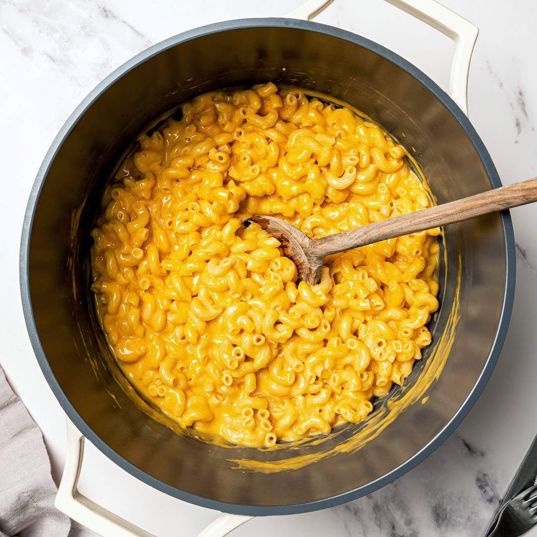 Pot of vegan mac and cheese with wooden spoon.