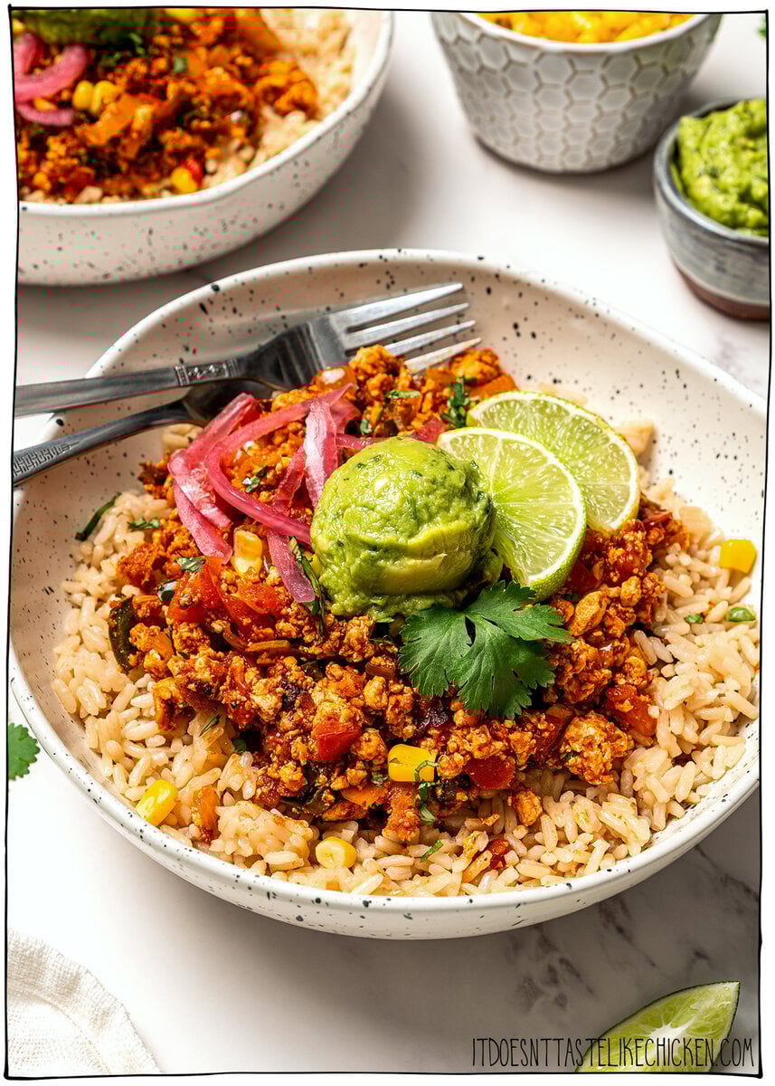 These smoky, saucy vegan sofritas are made in one pan with tofu, chipotle, and spices. Perfect for tacos, bowls, burritos, and meal prep! Burrito bowl topped with sofritas, guacamole, and lime wedges.