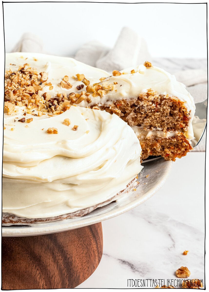Removing a slice of vegan carrot cake from a cake stand.