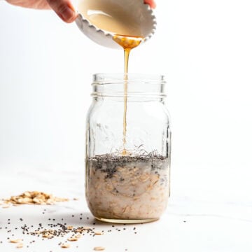 Pouring maple syrup into jar of overnight oats.