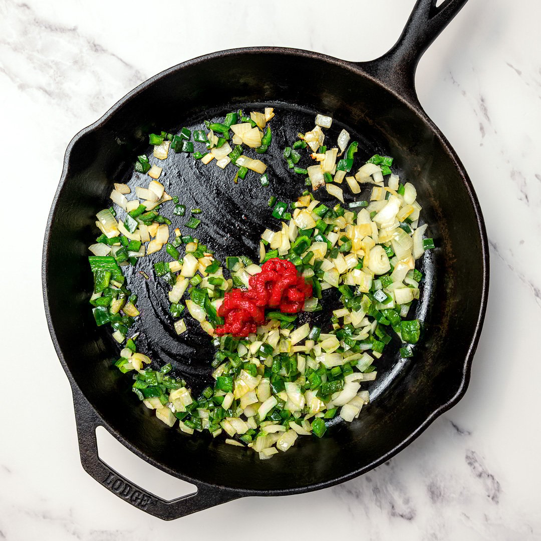 These smoky, saucy vegan sofritas are made in one pan with tofu, chipotle, and spices. Perfect for tacos, bowls, burritos, and meal prep! Tomato paste added to skillet with onions, garlic and poblano.