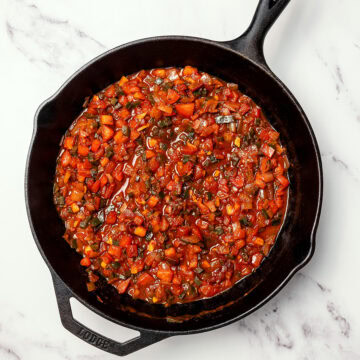 Tomatoes and peppers simmering in skillet.