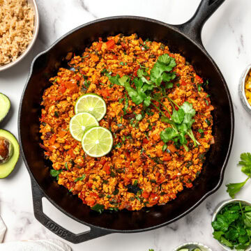 Skillet of tofu sofritas with lime slices and cilantro.