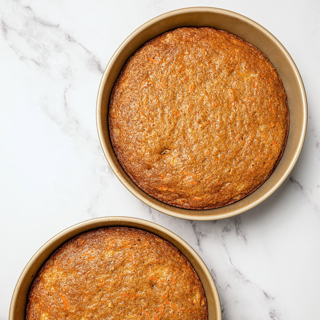 Two vegan carrot cake layers in round pans.