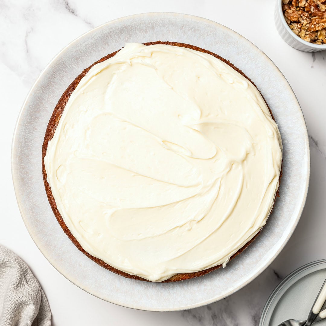 Vegan carrot cake topped with cream cheese frosting.