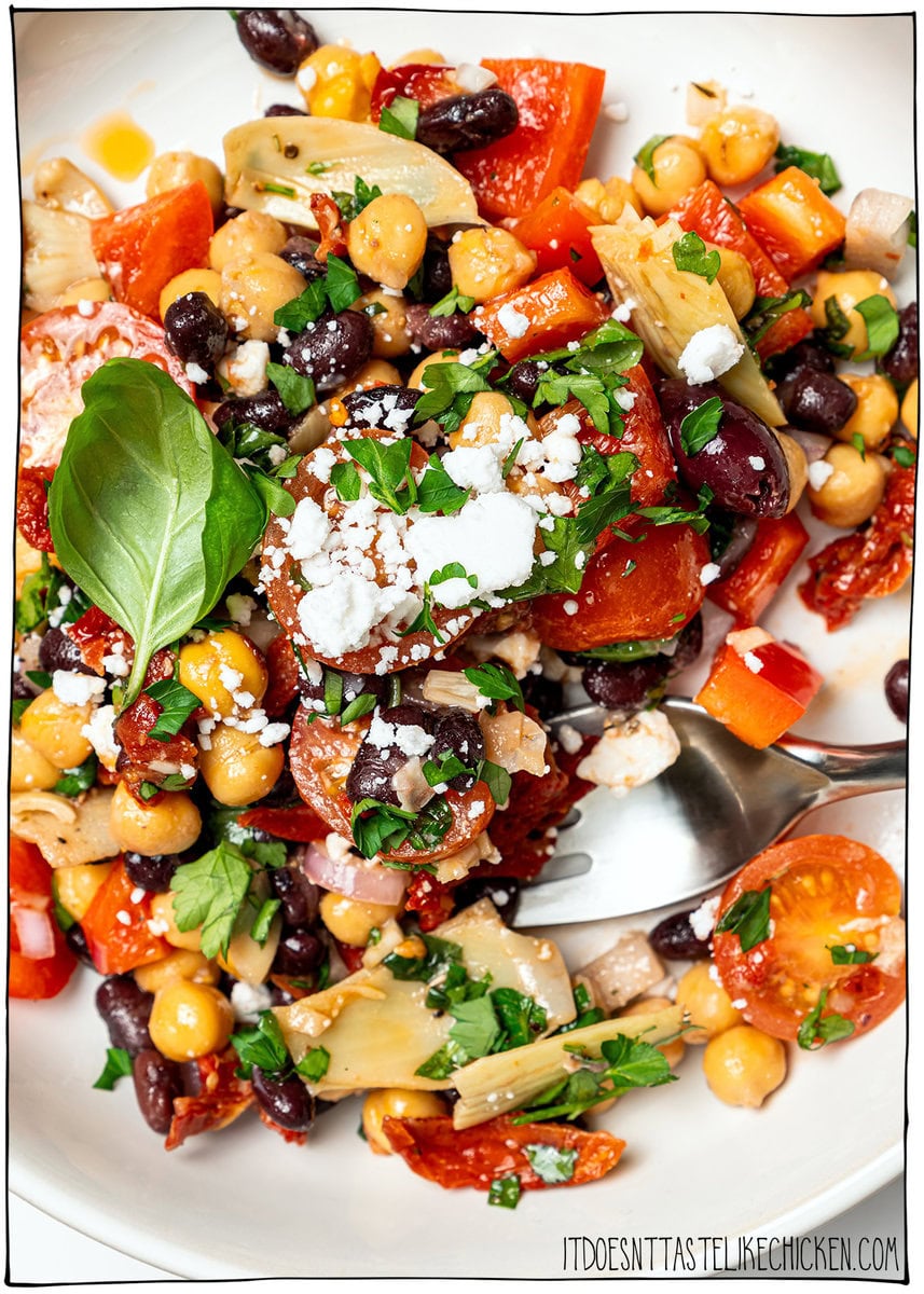 Dense bean salad packs hearty beans, crunchy veggies, and bold dressing into a satisfying make-ahead dish that stays tasty all week long! Bowl of dense bean salad with fork.