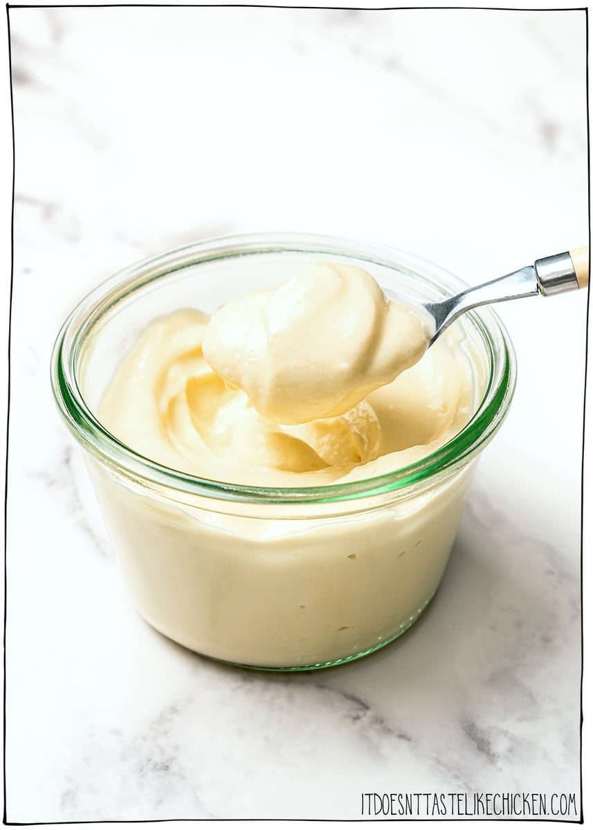 Creamy, garlicky, and full of bold flavor, this vegan garlic aioli is an easy recipe that instantly upgrades fries, sandwiches, and more! Spoonful of vegan garlic aioli held over jar.