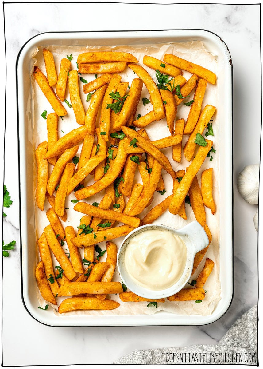 Creamy, garlicky, and full of bold flavor, this vegan garlic aioli is an easy recipe that instantly upgrades fries, sandwiches, and more! Pan of fries with bowl of vegan garlic aioli.