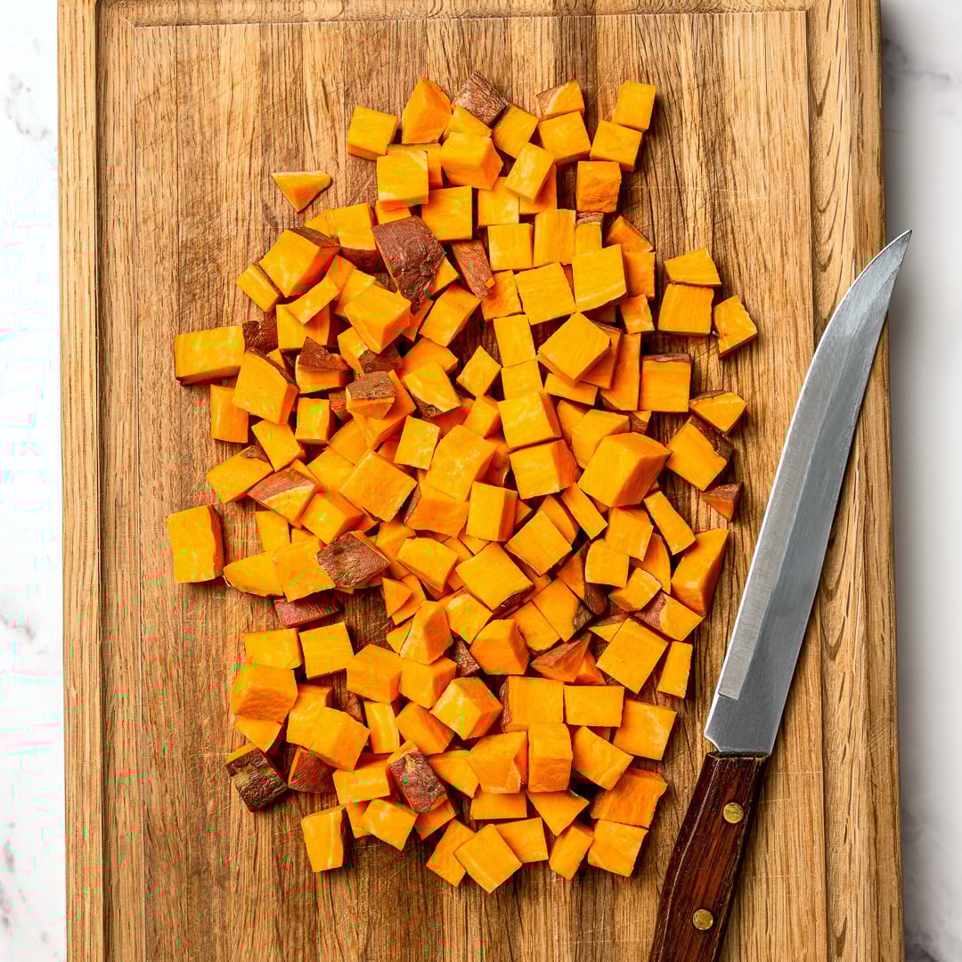 Air fryer sweet potatoes turn out crispy on the edges and tender inside, making a quick, flavorful side dish you'll make on frequent repeat! Cubed sweet potatoes on cutting board with knife.