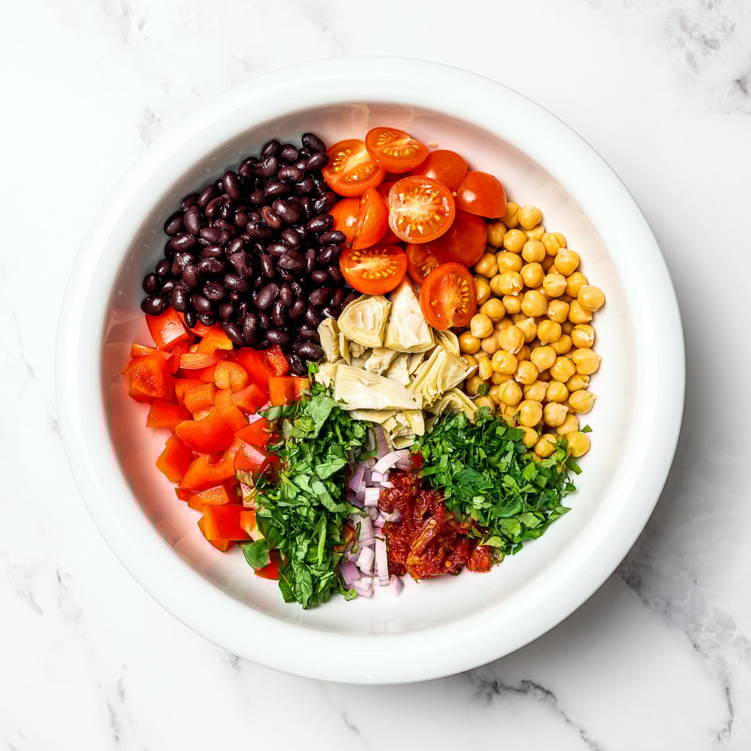 Dense bean salad packs hearty beans, crunchy veggies, and bold dressing into a satisfying make-ahead dish that stays tasty all week long! Ingredients for dense bean salad in mixing bowl.