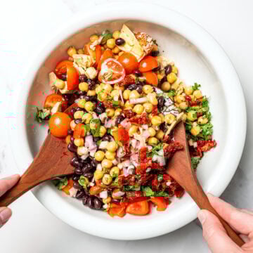Tossing dense bean salad in mixing bowl.