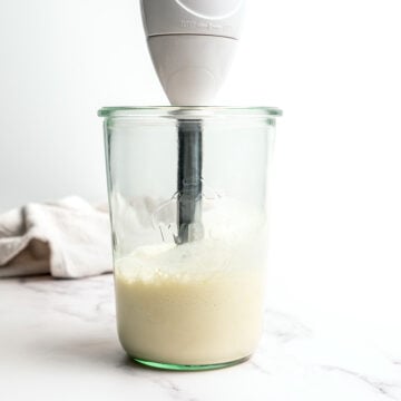 Immersion blender in jar of garlic aioli.