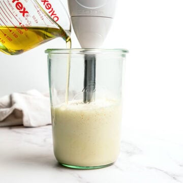 Drizzling oil into jar with immersion blender for vegan garlic aioli.