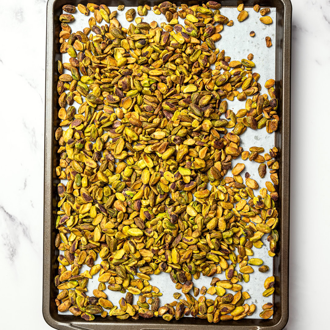 Roasted pistachios blend into a smooth homemade pistachio butter that tastes amazing on toast or straight from the spoon. Just 1 ingredient! Pistachios on sheet pan.