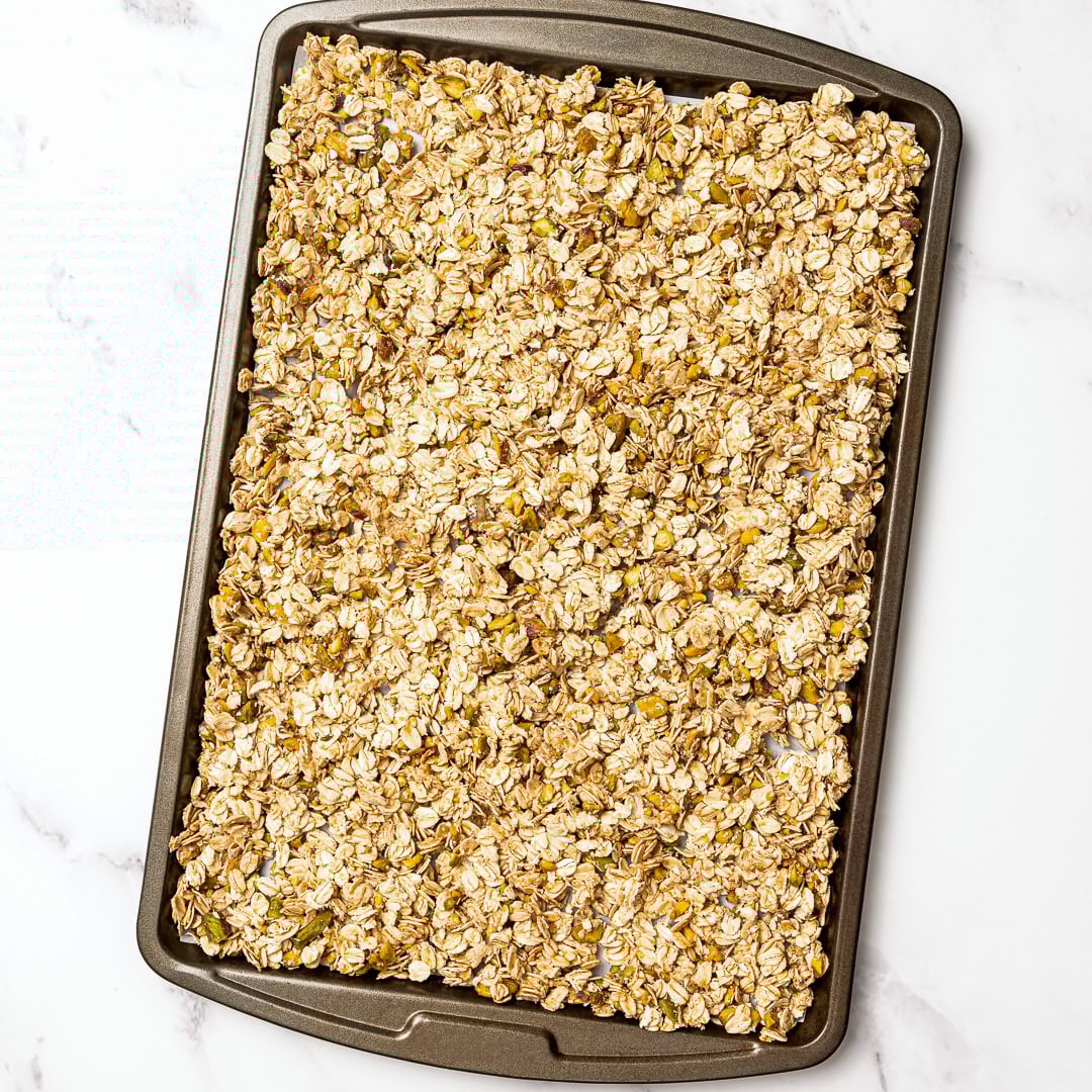 This pistachio cardamom granola is lightly sweet, perfectly crunchy, and infused with warm, aromatic cardamom. Easy 30 minute recipe! Pan of pistachio cardamom granola.