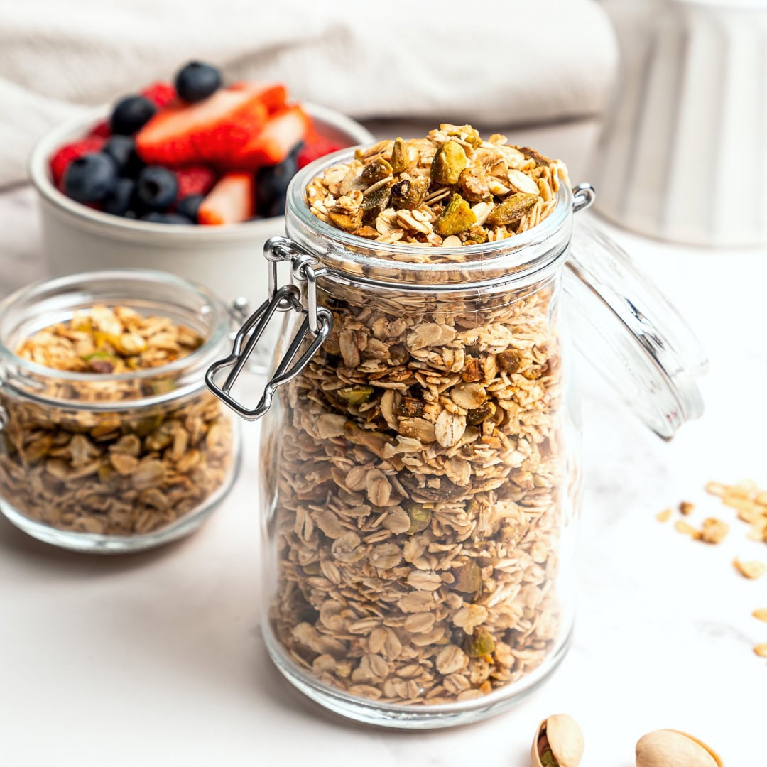 This pistachio cardamom granola is lightly sweet, perfectly crunchy, and infused with warm, aromatic cardamom. Easy 30 minute recipe! Jar of pistachio cardamom granola.