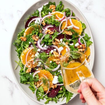 Pouring dressing onto roasted beet salad.