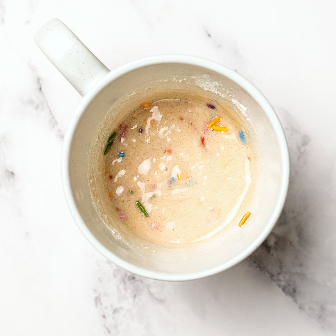Soft, fluffy, and ready in just 5 minutes, this vegan vanilla mug cake is the perfect single-serve dessert when a sweet craving hits! Vanilla cake batter in mug.