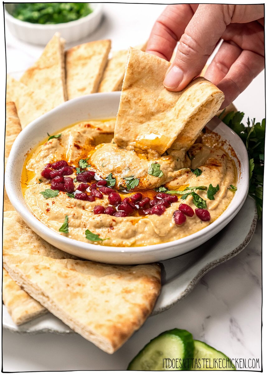 This easy baba ganoush is unbelievably creamy, smoky, and full of rich flavor, and you only need a handful of simple ingredients to make it! Dipping pita into bowl of baba ganoush.