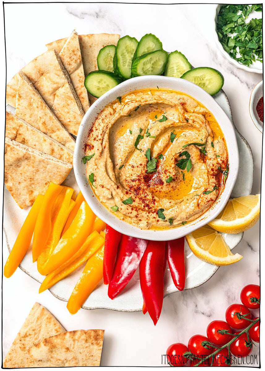 This easy baba ganoush is unbelievably creamy, smoky, and full of rich flavor, and you only need a handful of simple ingredients to make it! Bowl of baba ganoush on plate with veggies and pita bread.