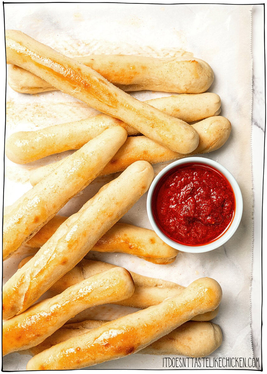 These vegan Olive Garden breadsticks are soft, fluffy, and brushed with buttery garlic salt, just like the restaurant. So irresistible! Vegan Olive Garden breadsticks with small bowl of marinara.