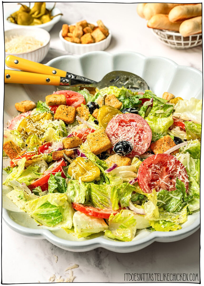 This vegan Olive Garden salad tastes just like the classic, with crisp lettuce, juicy tomatoes, olives and creamy, tangy Italian dressing! Serving bowl with vegan Olive Garden salad.