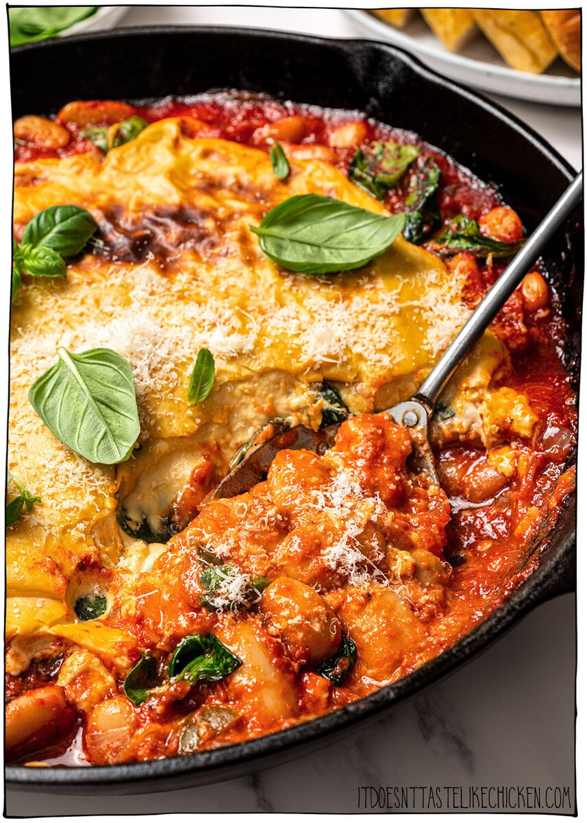 These pizza beans are an easy cozy dinner ready in 25 minutes! Creamy butter beans are simmered in marinara and topped with vegan cheese. Spoon scooping pizza beans from skillet.