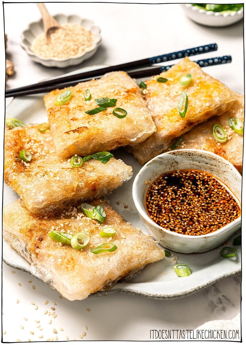 These vegan rice paper dumplings are crispy on the outside, chewy around the edges, with a savory cabbage and tofu filling. Viral on TikTok! Vegan rice paper dumplings on plate with dipping sauce and chopsticks.