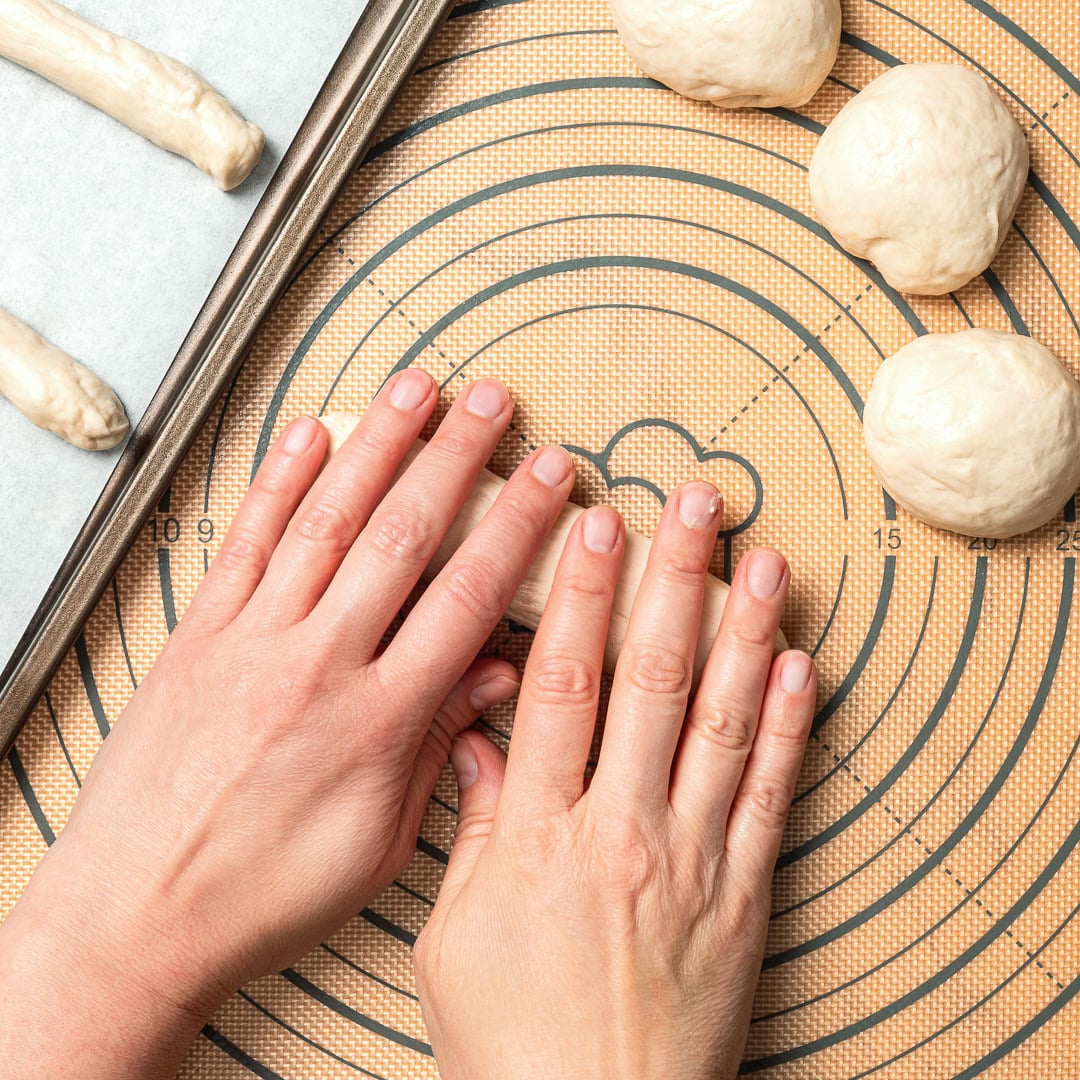 These vegan Olive Garden breadsticks are soft, fluffy, and brushed with buttery garlic salt, just like the restaurant. So irresistible! Hands rolling dough for vegan breadsticks.