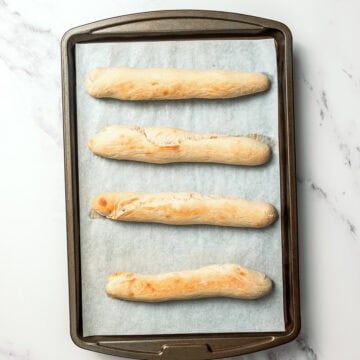 4 copycat Olive Garden breadsticks on parchment lined sheet pan.