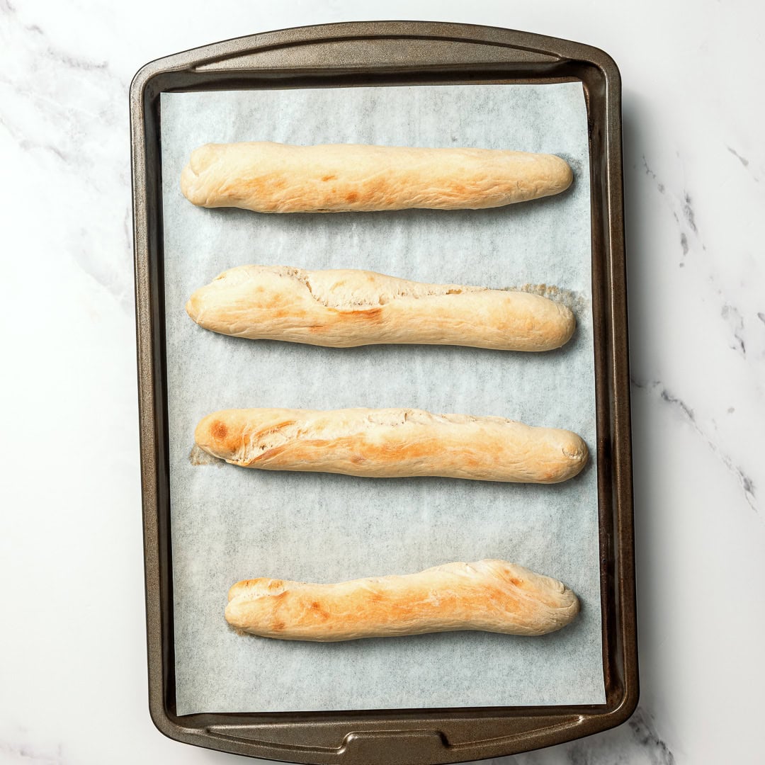 These vegan Olive Garden breadsticks are soft, fluffy, and brushed with buttery garlic salt, just like the restaurant. So irresistible! 4 copycat Olive Garden breadsticks on parchment lined sheet pan.
