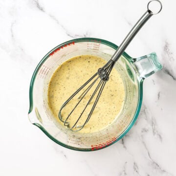 Creamy Italian dressing in liquid measuring cup with whisk.