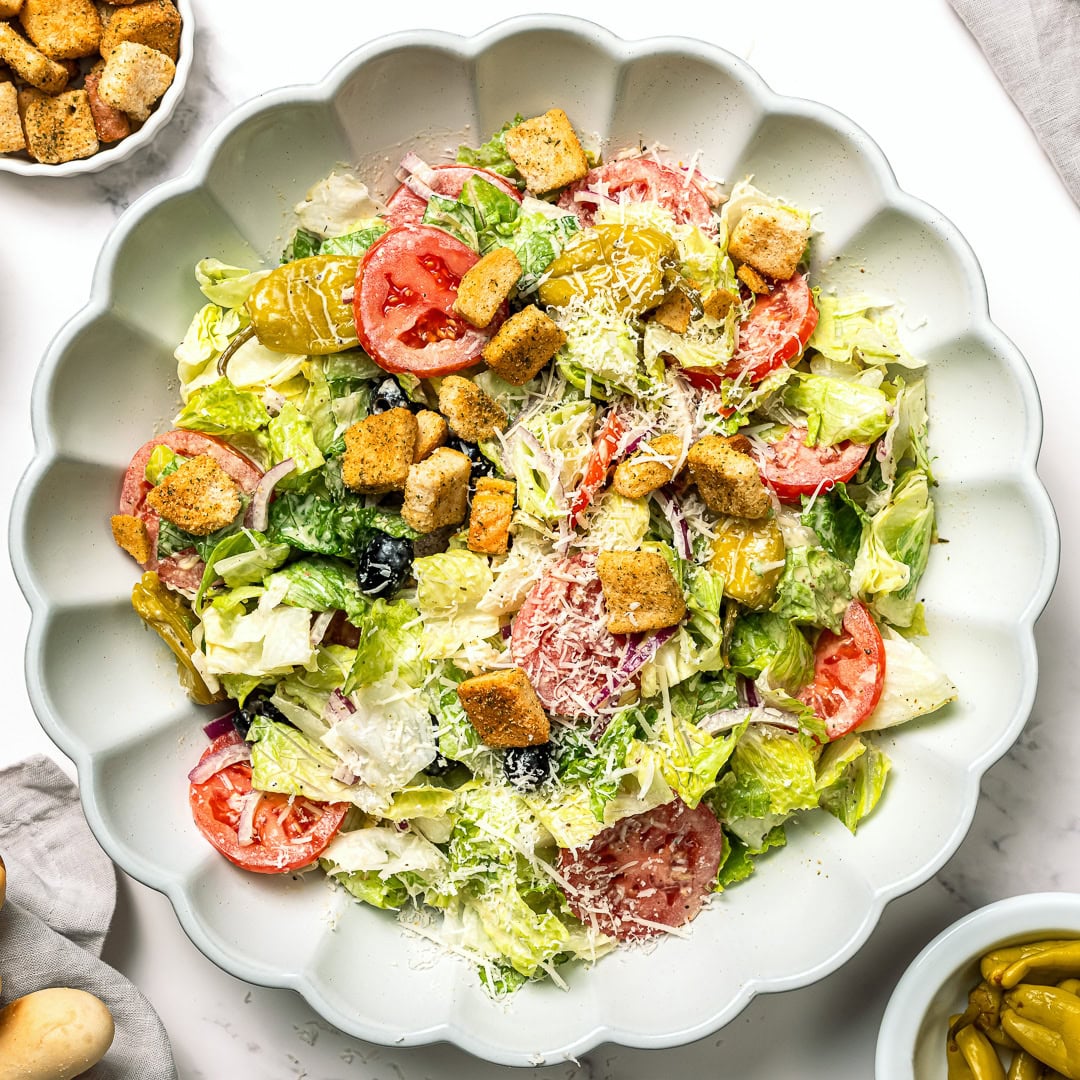 This vegan Olive Garden salad tastes just like the classic, with crisp lettuce, juicy tomatoes, olives and creamy, tangy Italian dressing! Bowl of vegan Olive Garden salad.