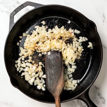 Onion, garlic, and seasonings cooking in cast iron skillet.